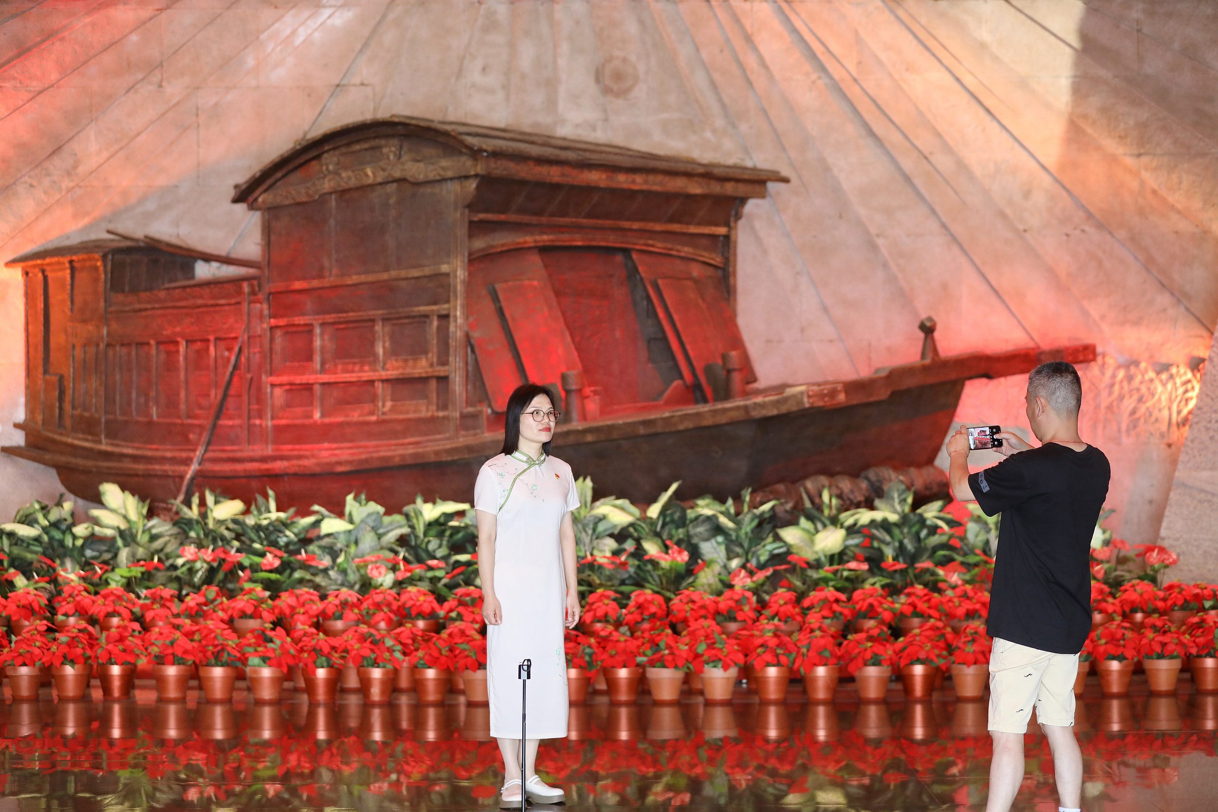 2025年6月24日，浙江嘉興，游客在南湖革命紀(jì)念館與紅船雕塑合影。（圖片來(lái)源：視覺(jué)中國(guó)）